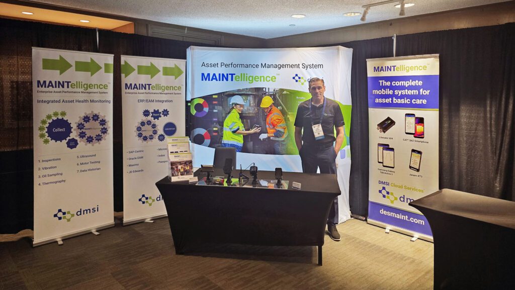 John Macsween standing at the DMSI booth, showcasing handheld devices. 