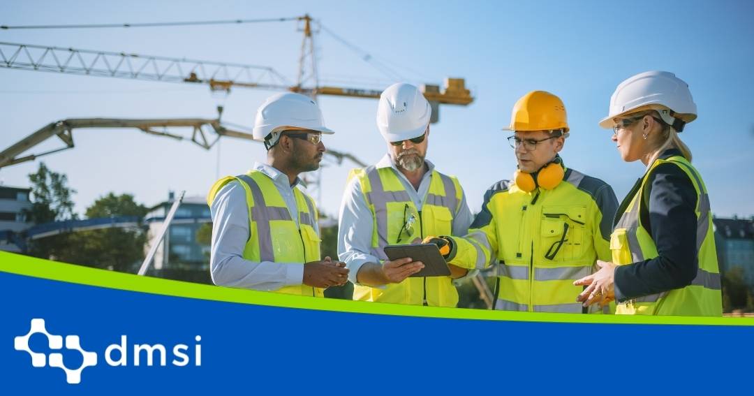 Four engineers in a facility, huddled and looking at a tablet.