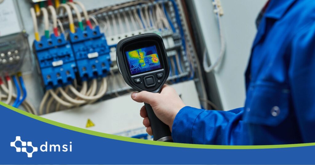 Technician uses a thermal imaging camera to inspect an electrical control panel for hot spots.