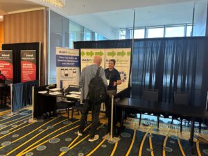 DMSI’s Ilyass speaks with an attendee at the MAINTelligence™ booth at MainTrain 2026, next to a French WorkMT banner