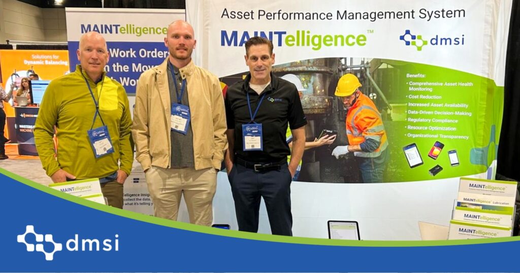 DMSI and T5 Group team members with conference lanyards at the SMRP 2026 booth in Raleigh, beside brochure racks and a backdrop of plant workers inspecting equipment