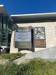 Raleigh Convention Center exterior with a welcome sign for the Society for Maintenance and Reliability Professionals (SMRP) 2026 conference